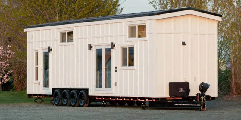 A white modern RV home on wheels parked outdoors