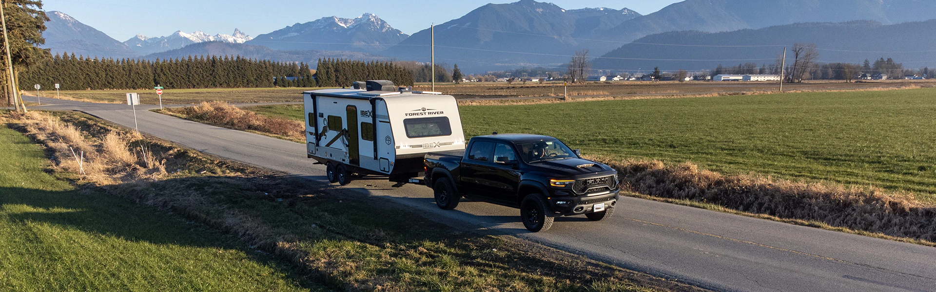 A truck hauiing an RV on the road with mountain view