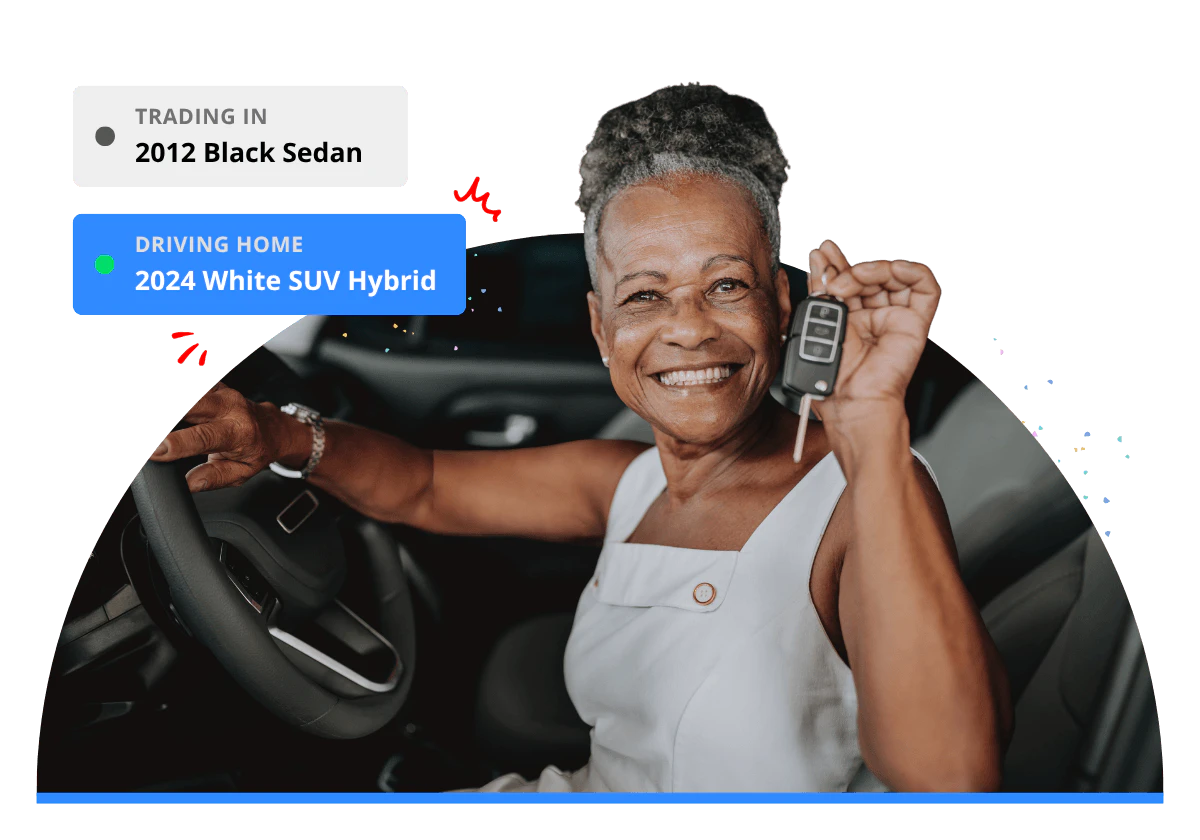 A lady smiling sitting in a car holding the car key after a vehicle trade-in