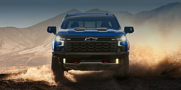 blue Chevrolet Silverado driving through a desert