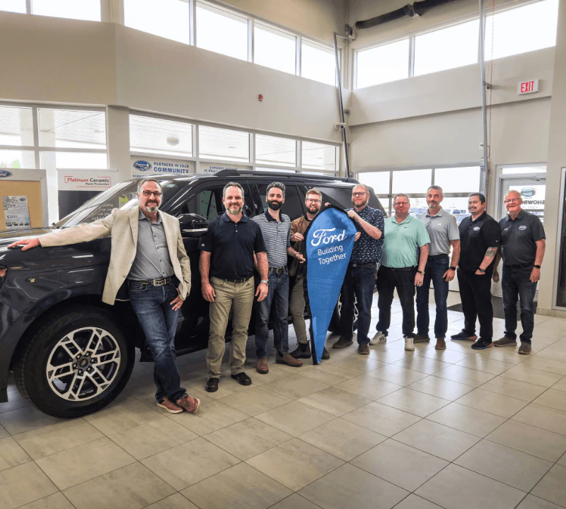 Cypress Motors team posing in front of a car in the dealership