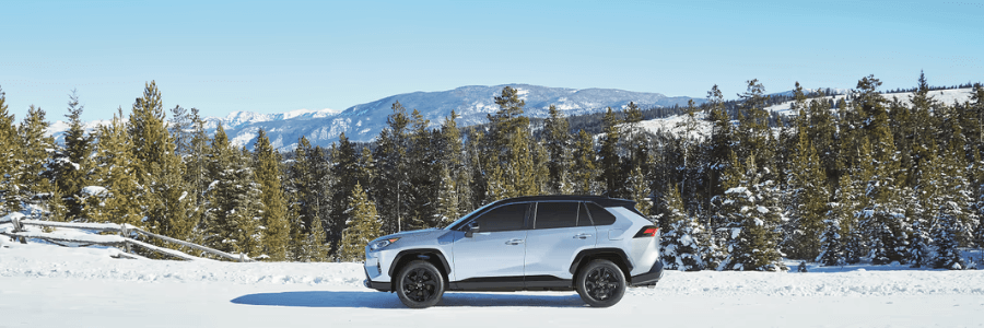 toyota suv parked in the snow with mountain view