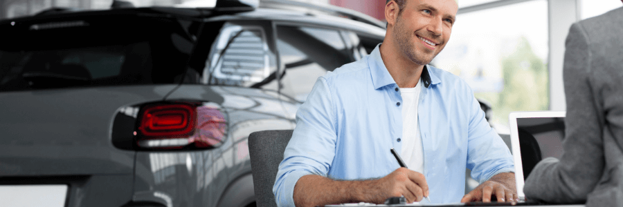 man at a car dealership signing documents