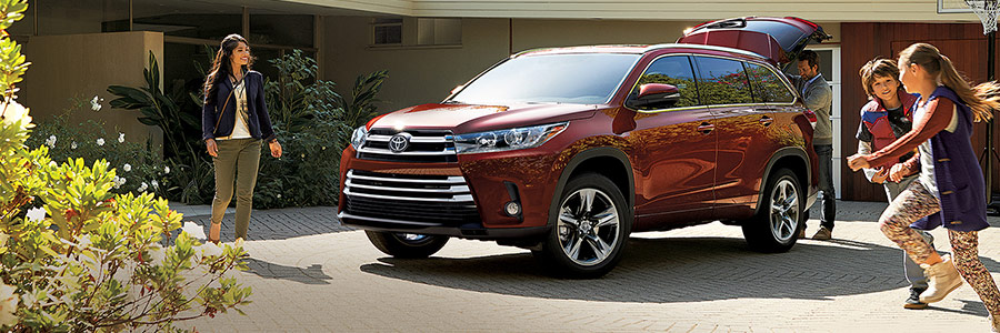 family in driveway next to toyota highlander