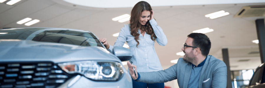 woman and sales rep looking at a used car at a dealership