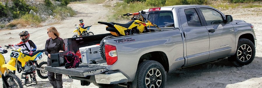 A silver Toyota Tundra parks while friends load yellow dirt bikes in bed
