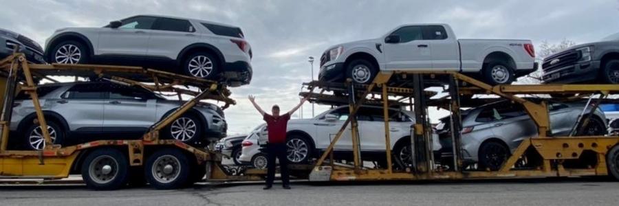 Person standing in front of a truck full of cars
