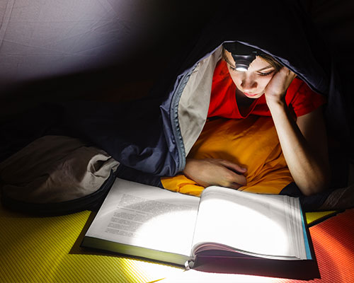 Boy reading at night with a flashlight on his head