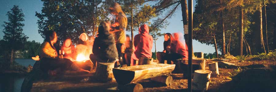 family and friends around a fire at a camp ground