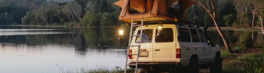 White van with tent trailer near a lake