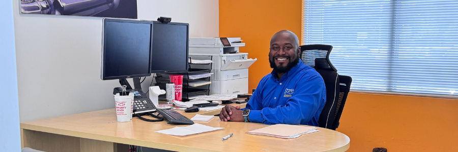 A smiling Strosnider Chevrolet team member sits at a desk wearing a blue 