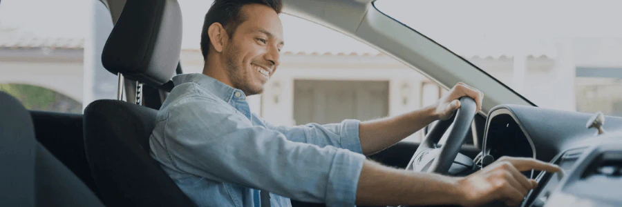 A man sitting in a driver seat inside of a car