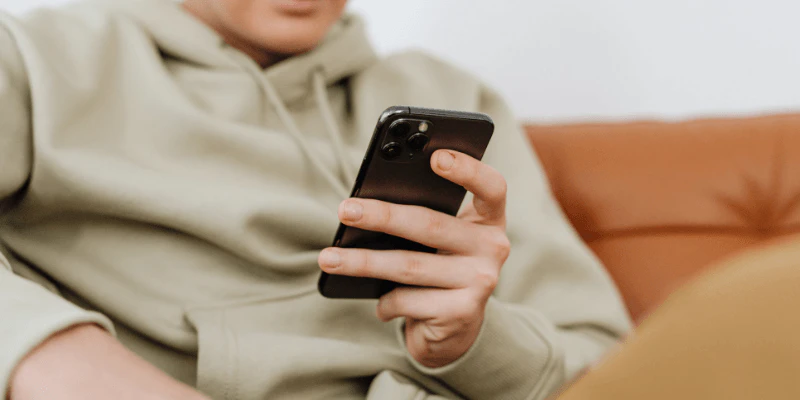 A guy wth grey sweater looking at phone