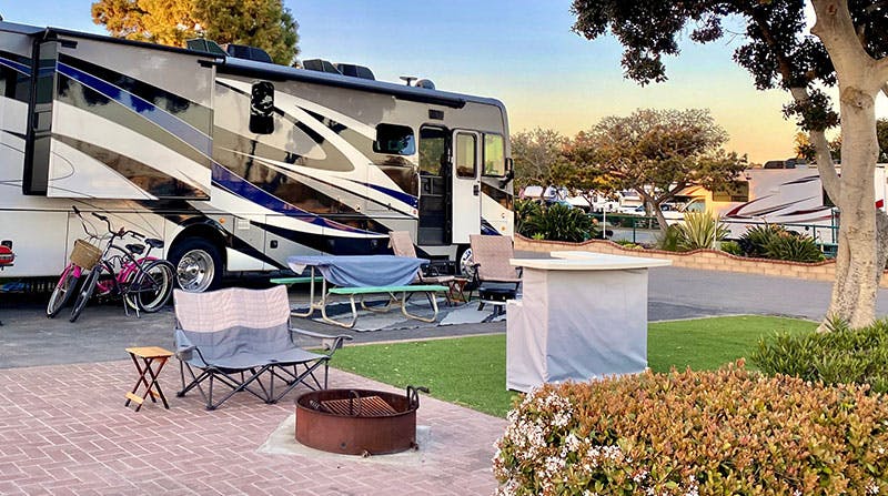 rv-in-a-camping-space-with-fire-ring-chair-bikes