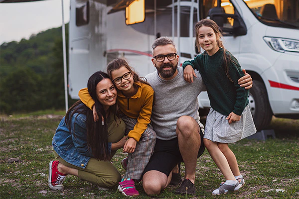 A family of 4 taking picture in front of an RV