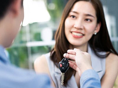 dealer handing car key to new owner