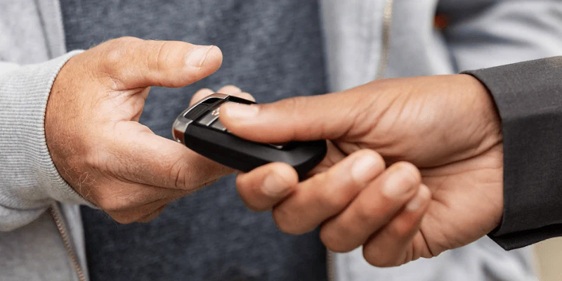 Close-up of a car key fob being handed from a dealer to a customer