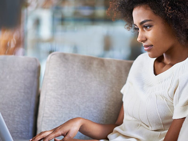 woman on the couch researching on her laptop