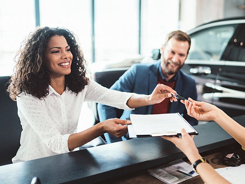 happy couple handing over a form to a service rep
