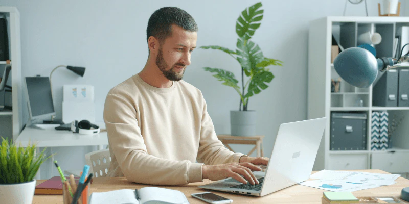 A man sitting on a desk using a laptop
