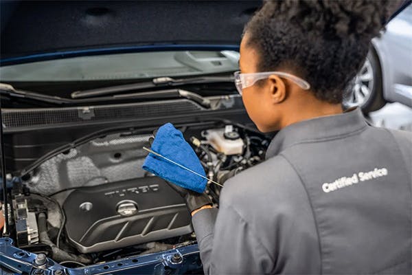 female service technician checking oil levels of a vehicle