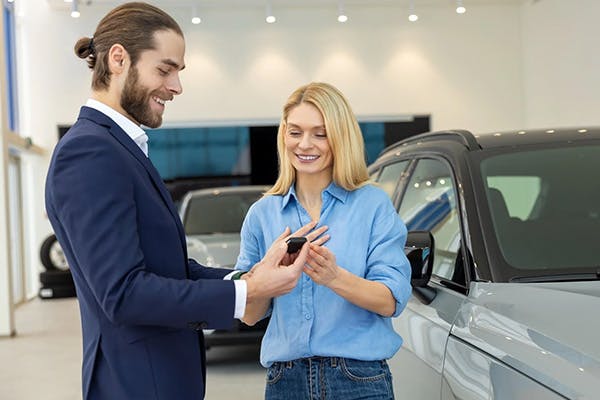 salesmen smiling and showing a happy customer something on their mobile phone