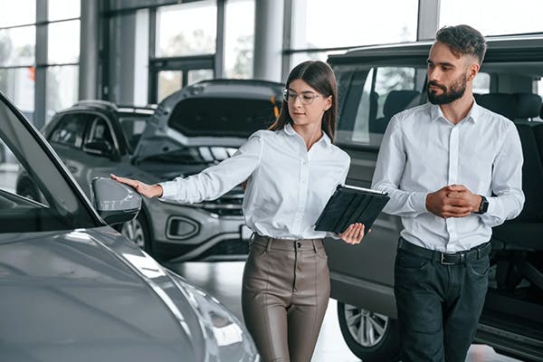 man and woman admiring a vehicle on a dealership showroom