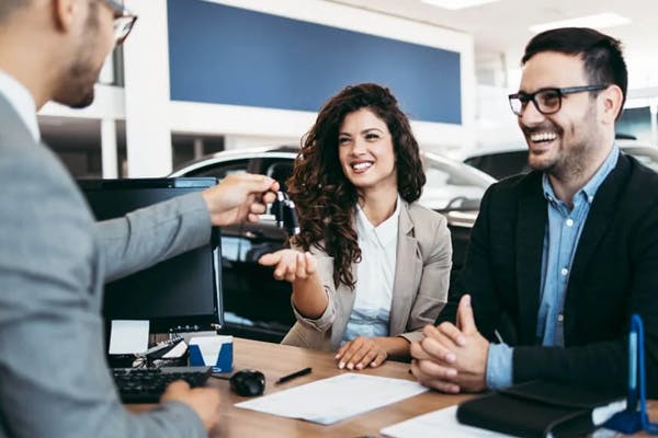 happy couple receiving their brand new car from a salesmen