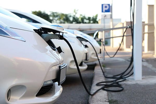 line of electric vehicles plugged in at a public charging station