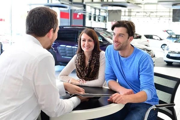 man and woman talking to a finance employee at their local dealership