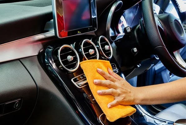 person wiping down the interior of their vehicle with a cloth