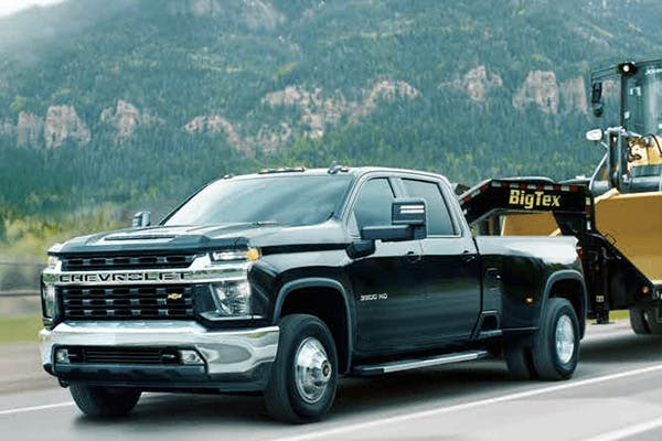 Black Chevrolet Silverado transporting heavy equipment vehicle