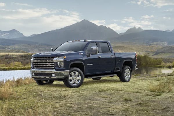 Black Chevrolet Silverado on grass with mountains in the background