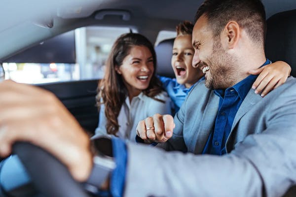 family happily laughing together in their vehicle