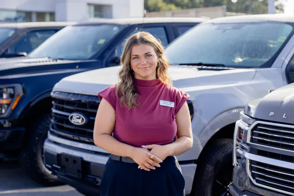 An employee standing in front of a lined up Ford trucks in the lot
