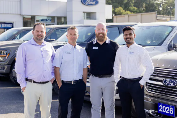 Employeees standing in front of a lined up Ford trucks in the lot