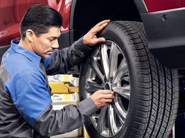 a for service repairman is checking the tires on a vehicle