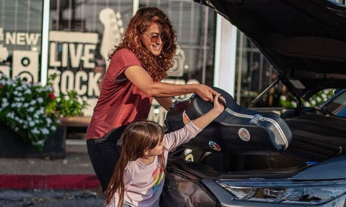 Woman dand her child packing  the trunk of their new ford