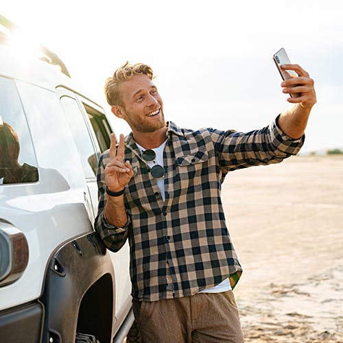Man happily taking a selfie with their new vehicle